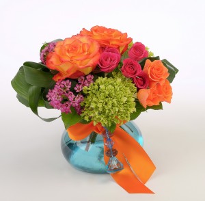 Orange, hot pink and green flowers in blue vase